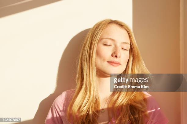 portrait of young woman, outdoors, in sunlight, eyes closed - augen geschlossen stock-fotos und bilder