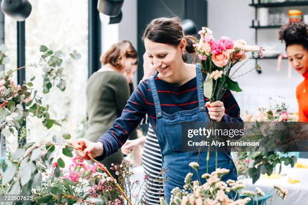 florist student selecting cut flowers at flower arranging workshop - jeans latzhose frau stock-fotos und bilder