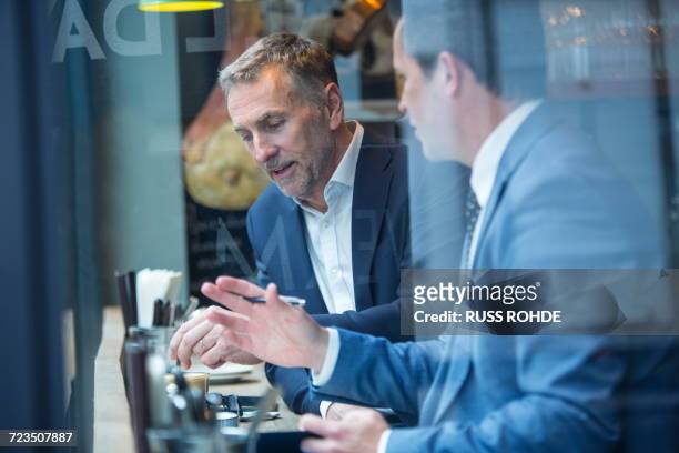 two businessmen having discussion in restaurant window seat - concept updates stockfoto's en -beelden