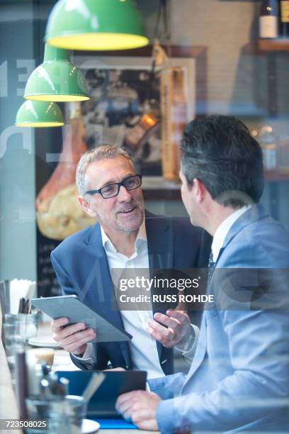 two businessmen having discussion in restaurant window seat - actualización comunicación fotografías e imágenes de stock