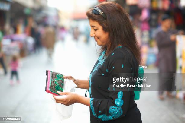 mature female tourist looking beaded purse on market stall, sharjah, united arab emirates - west asia stock pictures, royalty-free photos & images