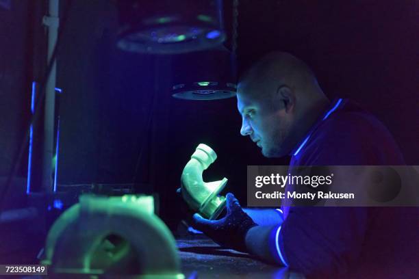 worker using ultra-violet light to test for cracks in components in precision casting factory - uv light stock pictures, royalty-free photos & images