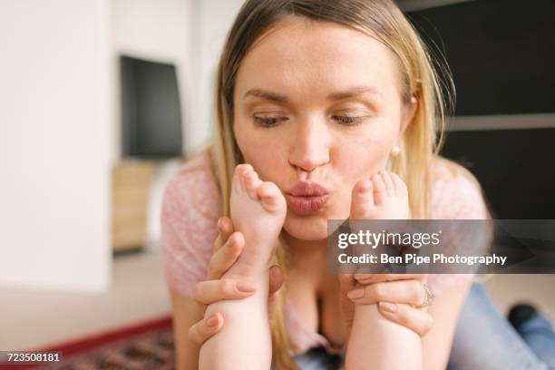 mother kissing baby on rug - kissing feet stock pictures, royalty-free photos & images