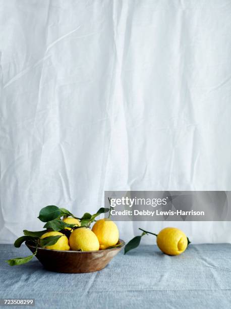 bowl of fresh lemons in bowl on tablecloth - still life stock pictures, royalty-free photos & images