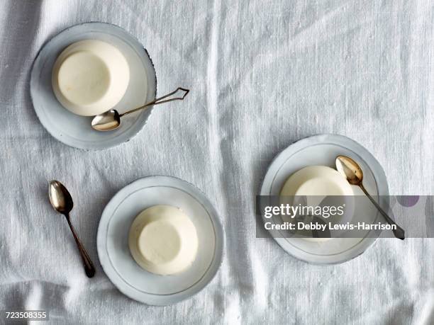 overhead view of panna cotta desserts on saucers - panna cotta stock pictures, royalty-free photos & images