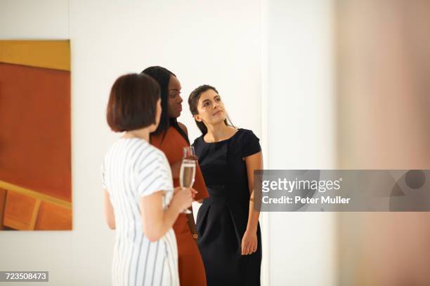 three women looking at oil paintings at art gallery opening - friends museum fotografías e imágenes de stock