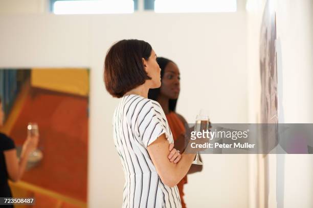 two women looking at oil paintings at art gallery opening - art gallery opening stock pictures, royalty-free photos & images