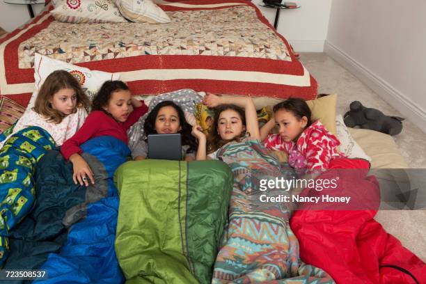 girls in sleeping bags at slumber party using digital tablet - slumber party - fotografias e filmes do acervo