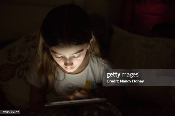 girl in darkness illuminated by light from digital tablet - vulnerability stock pictures, royalty-free photos & images