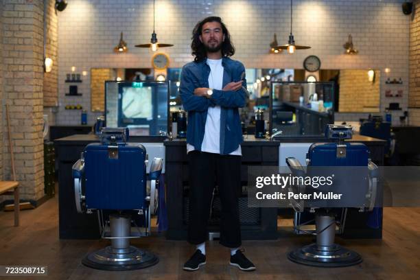 portrait of barber with arms folded in retro style barber shop - double denim stock-fotos und bilder