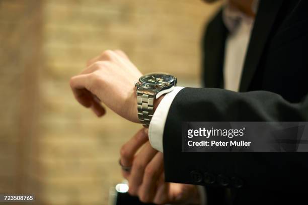 close up of businessman fastening wristwatch - kleine uhr stock-fotos und bilder