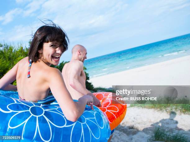 couple in floats running down to the beach, mallorca, spain - pony play stock-fotos und bilder