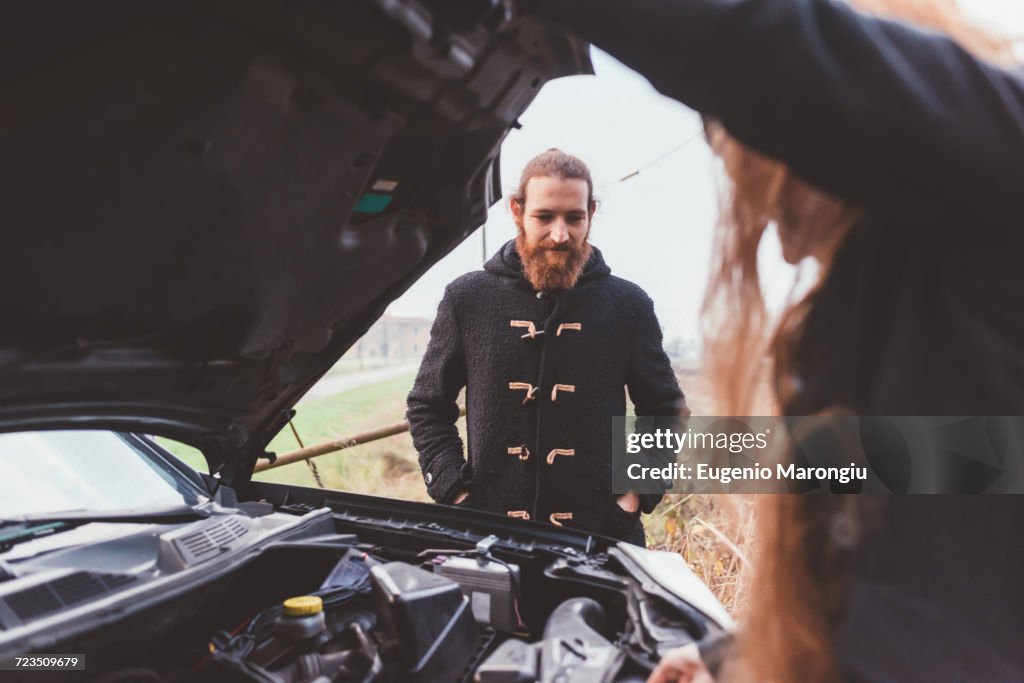 Couple looking at car engine on roadside