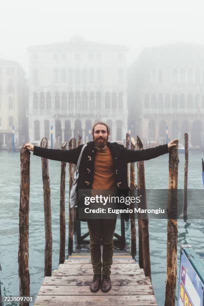 portrait of mid adult man on misty canal pier, venice, italy - duffle coat stock pictures, royalty-free photos & images