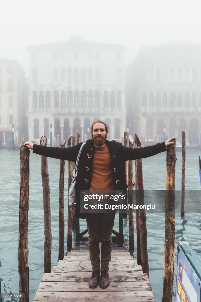 Portrait of mid adult man on misty canal pier, Venice, Italy