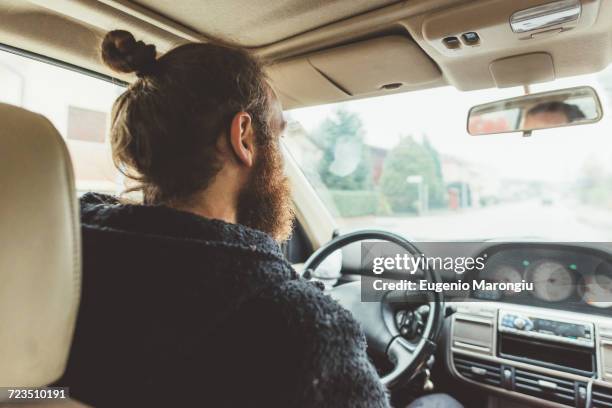 over shoulder view of bearded man driving a car - knitted car stock pictures, royalty-free photos & images