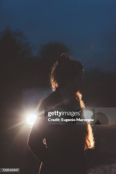 woman in front of car headlights on roadside at night - mysterious blond woman stock pictures, royalty-free photos & images