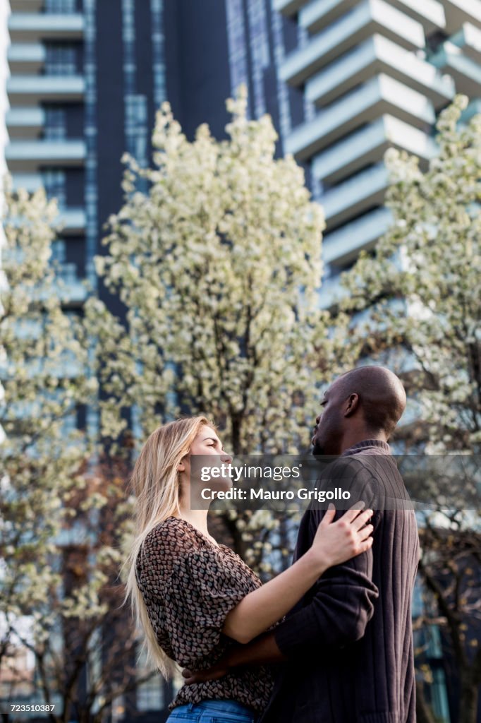 Young couple hugging and gazing at each other in city