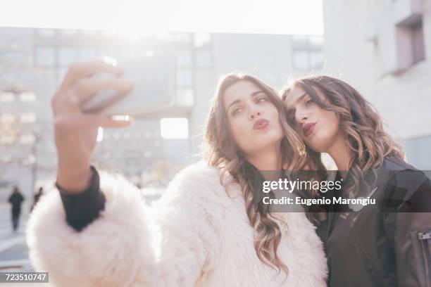 twin sisters, outdoors, taking selfie, using smartphone - identical twin stock pictures, royalty-free photos & images