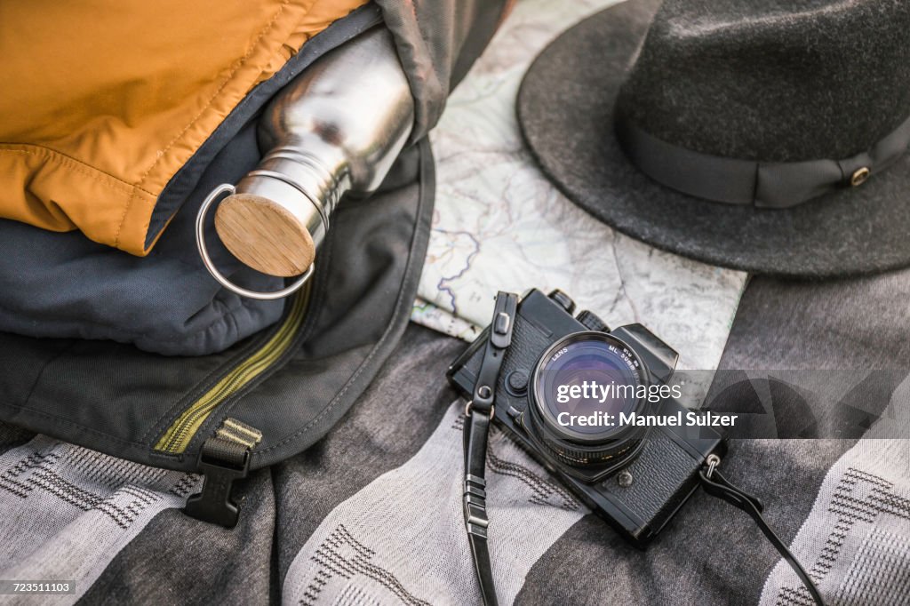 Still life of blanker, SLR camera, drinking flask and hat