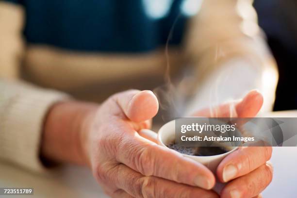 midsection of senior man holding coffee cup at table - hot beverage stock-fotos und bilder