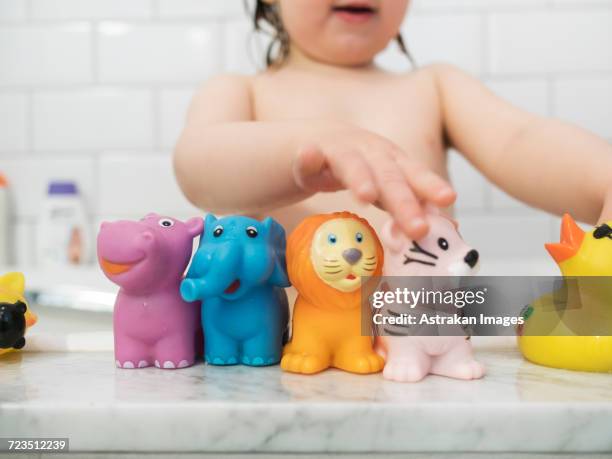 midsection of girl playing with rubber toys in bathtub - 動物のおもちゃ ストックフォトと画像