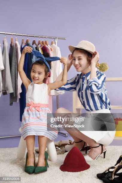 young mothers and children try to wear a hat - girl changing room shop stock pictures, royalty-free photos & images