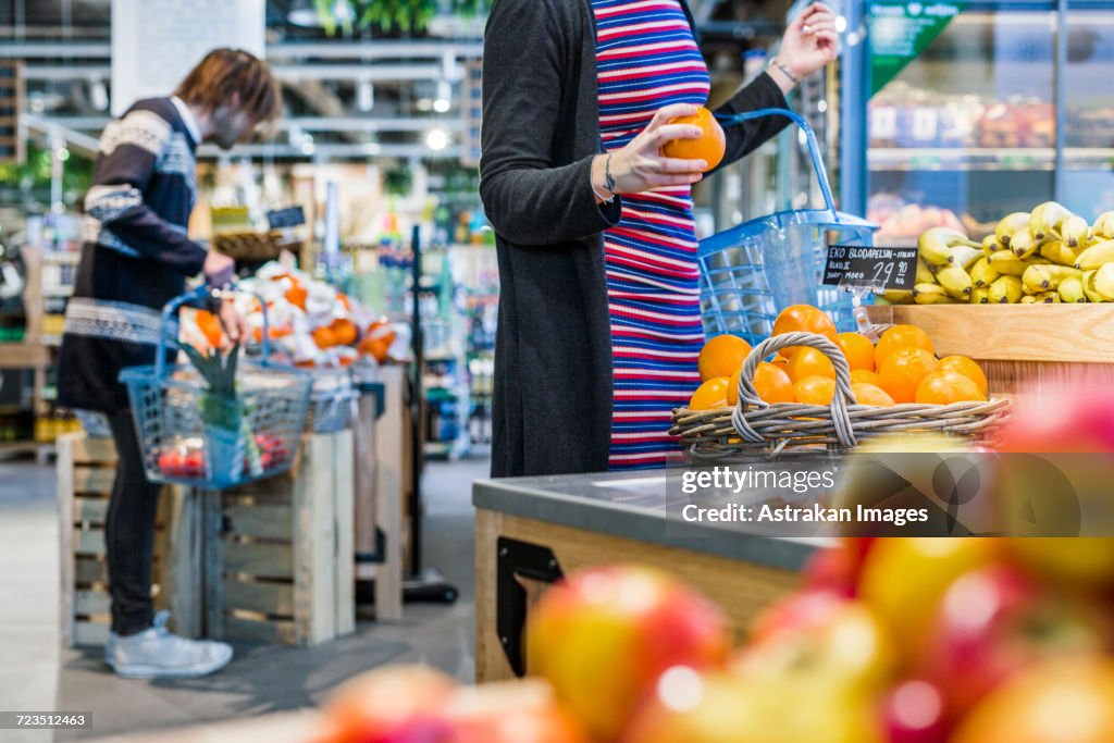 People shopping fruits while standing in supermarket