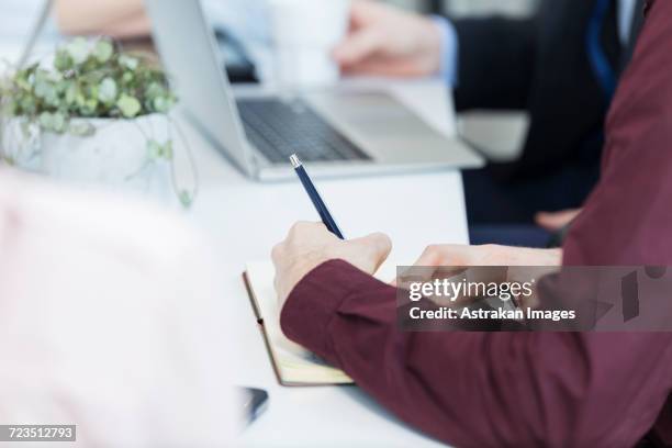 cropped image of businessman writing in book in meeting - arab businesswoman with books fotografías e imágenes de stock