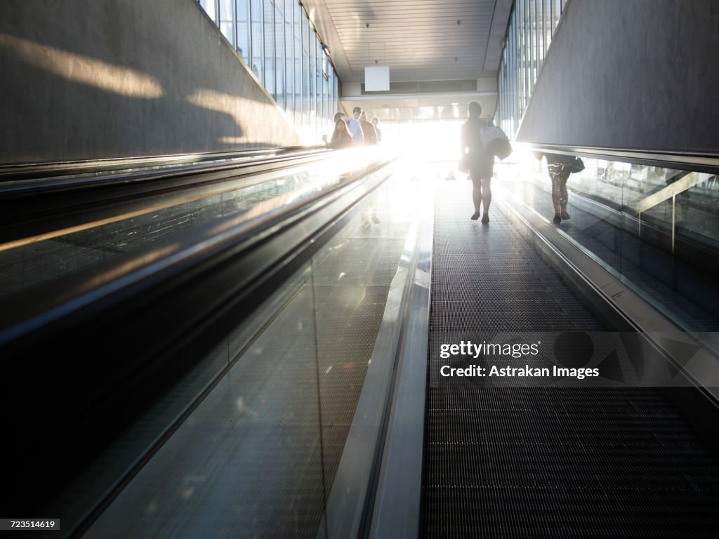 Rear view of woman walking on moving walkway