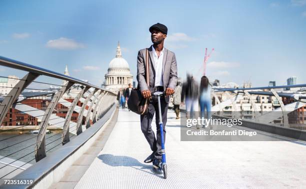 businessman on scooter, millennium bridge, london, uk - millennium bridge londra foto e immagini stock