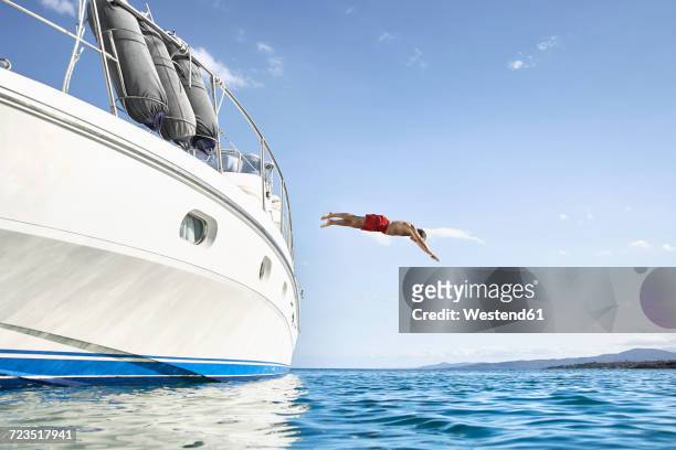 man jumping off his motor yacht - jumping of boat foto e immagini stock