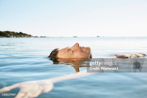 relaxed mature man floating in the sea - floating on water stock pictures, royalty-free photos & images