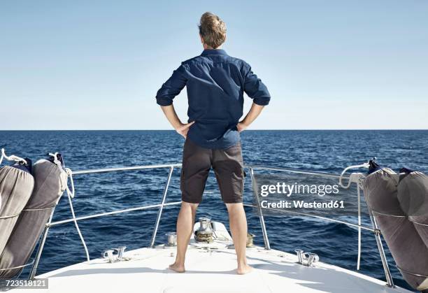 back view of mature man standing on his motor yacht with hands on hips - luxury yacht stock pictures, royalty-free photos & images