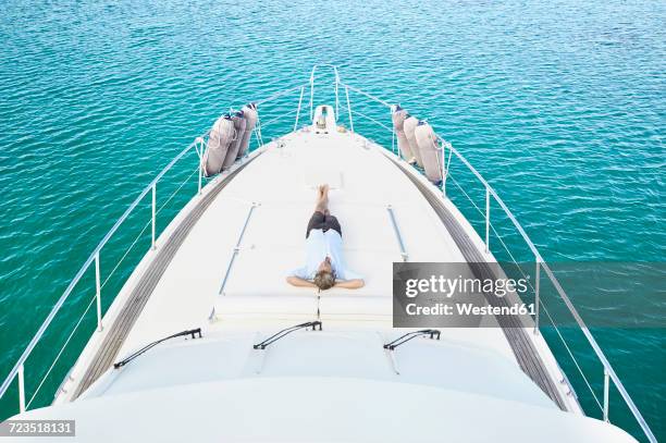 mature man lying on deck of his motor yacht - motor yacht stock pictures, royalty-free photos & images