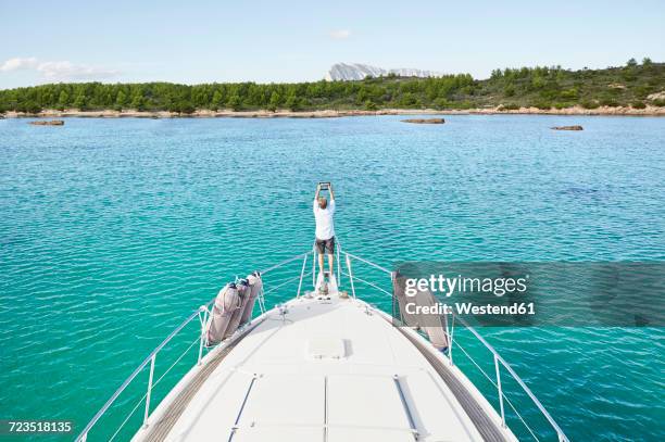 back view of man standing at bow of his motor yacht taking picture with tablet - boat deck stock pictures, royalty-free photos & images