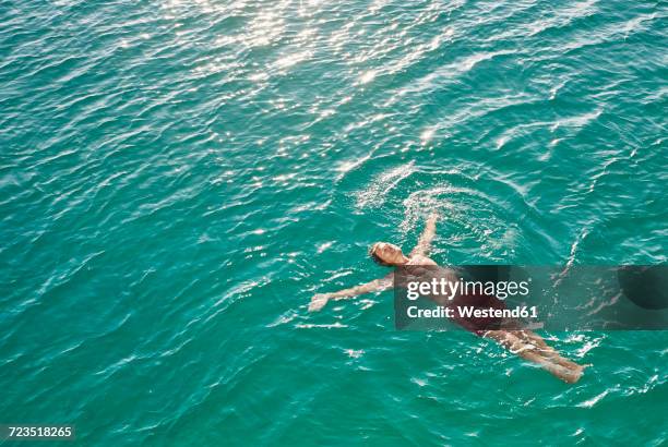 mature man floating in emerald water - easy stockfoto's en -beelden