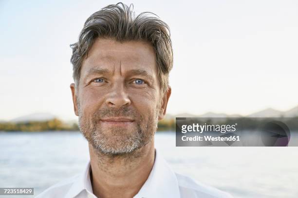 portrait of smiling mature man with stubble in front of the sea - hair stubble stockfoto's en -beelden
