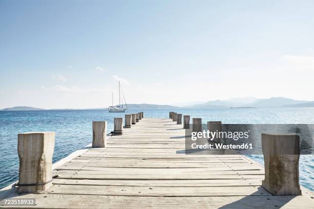 empty jetty and saling boat in the background - pier stock-fotos und bilder