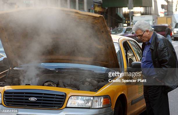 Taxi driver looks at his overheating engine February 22, 2002 in New York City. Claiming that the taxi industry can not attract enough drivers, New...