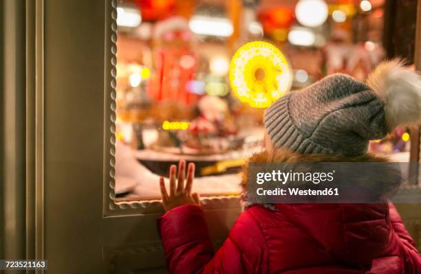 girl looking at a christmas shop window - window shopping stock-fotos und bilder