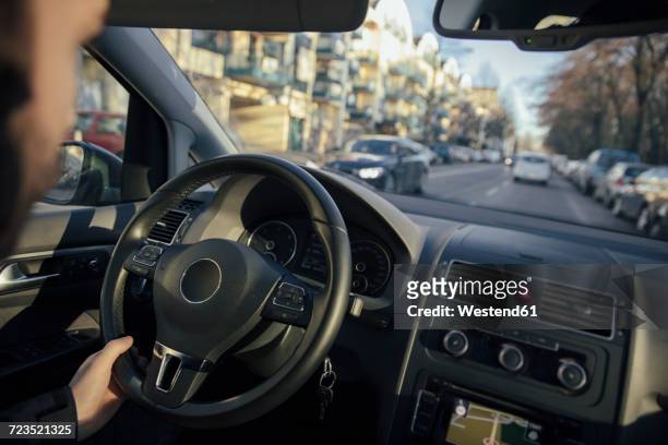 steering wheel and hand of a man driving a car through the city - point of view driving stock-fotos und bilder