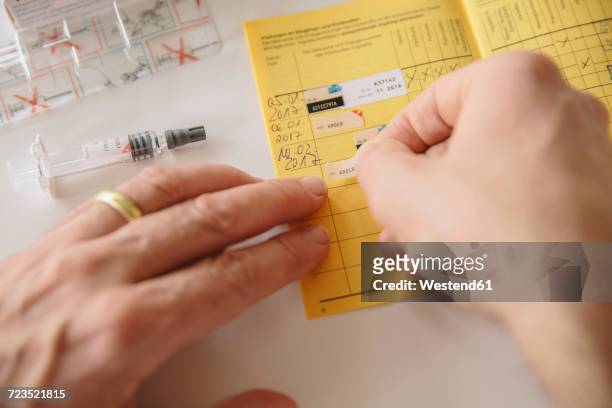 hand putting sticker in vaccination pass - immunisation certificate stock-fotos und bilder