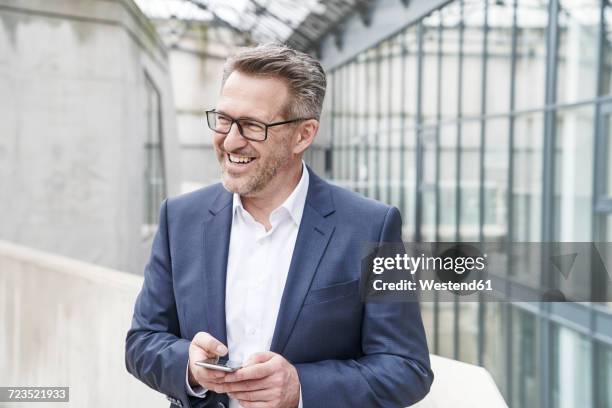 portrait of happy businessman with cell phone - mann anzug gebäude objekt draussen stock-fotos und bilder