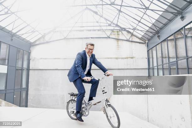 businessman riding folding bicycle - folding bike stockfoto's en -beelden