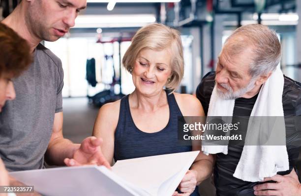 group of fit seniors and personal trainer in gym looking in folder - teacher with folder stock pictures, royalty-free photos & images