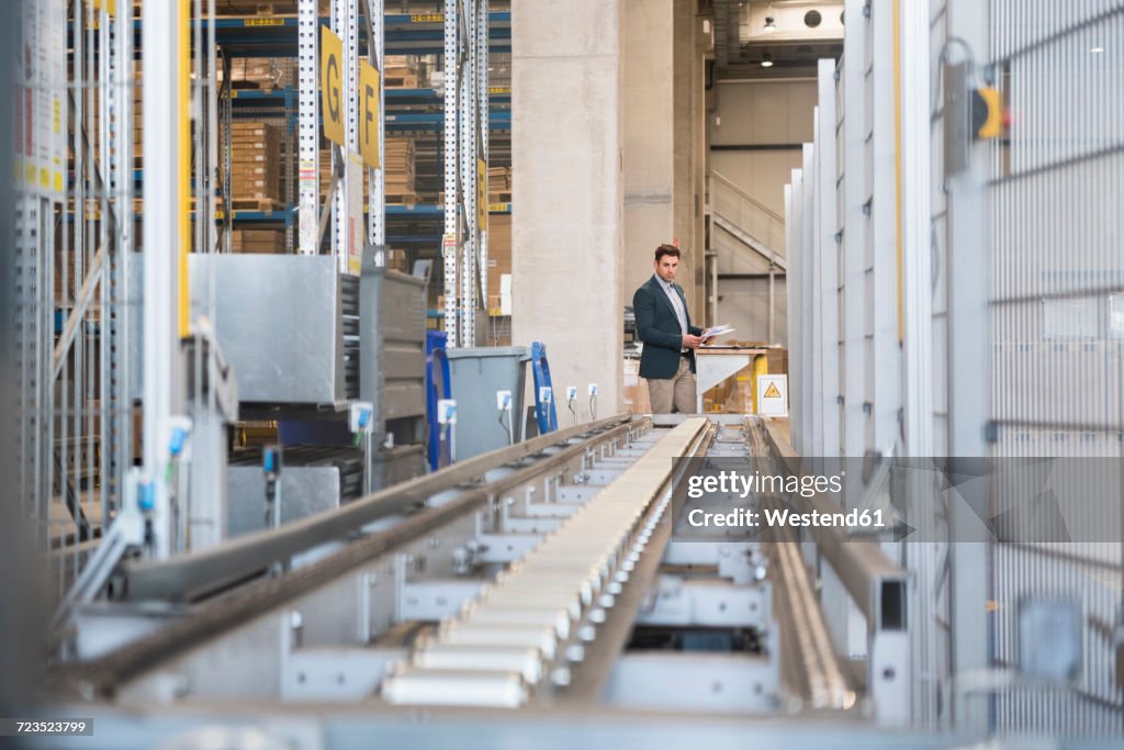 Businessman at conveyor belt in factory