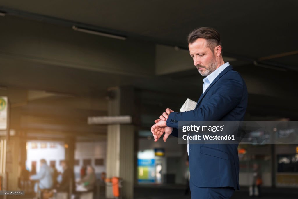 Businessman waiting at bus terminal checking the time