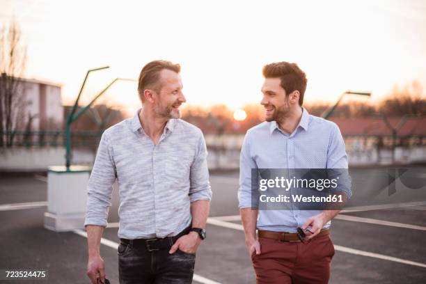 two friends walking and talking at sunset - businessmen casual not phone walking stock pictures, royalty-free photos & images