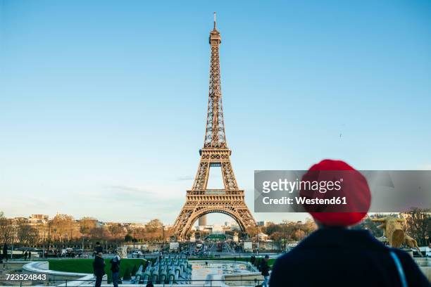 france, paris, view to eiffel tower with back view of young woman standing in the foreground - paris france stock-fotos und bilder